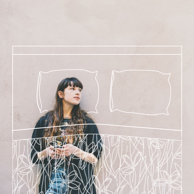 Woman leaning against a blank wall while holding a phone