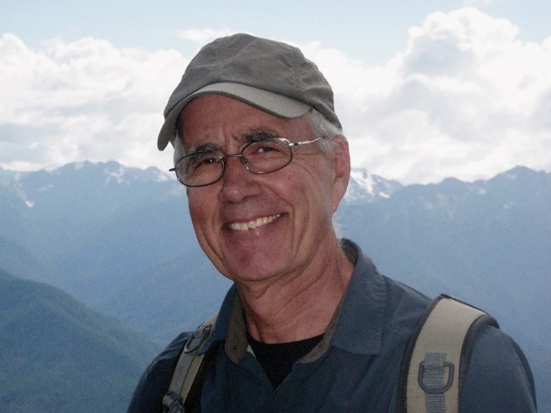 Photo of Dave Iverson hiking with snow-covered mountains in the back